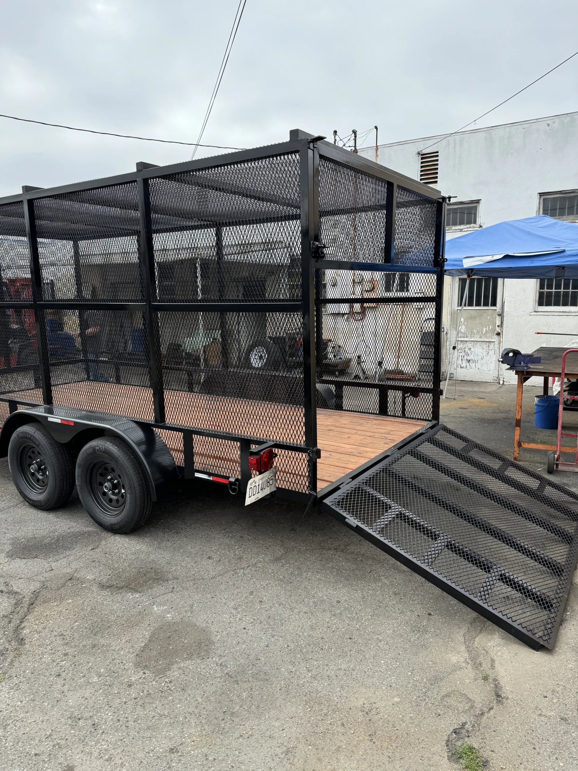 Landscaping cage trailer with fold-down mesh rear ramp gate after repair and fabrication